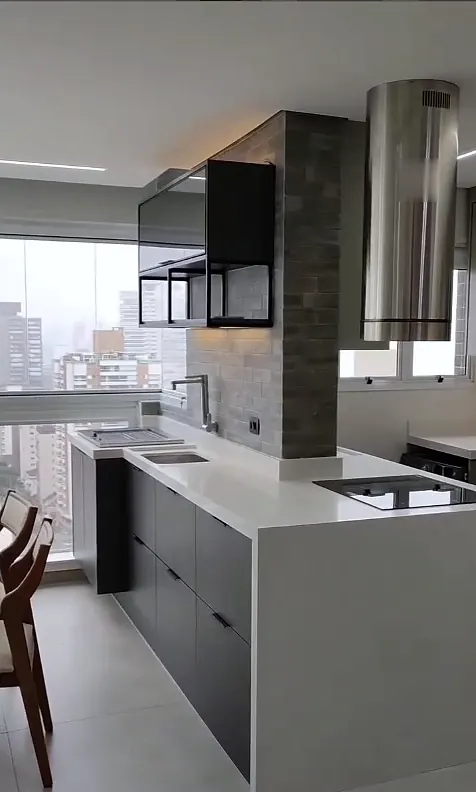 Cozinha integrada vista de lado, com coifa de inox, armários escuros e varanda ao fundo