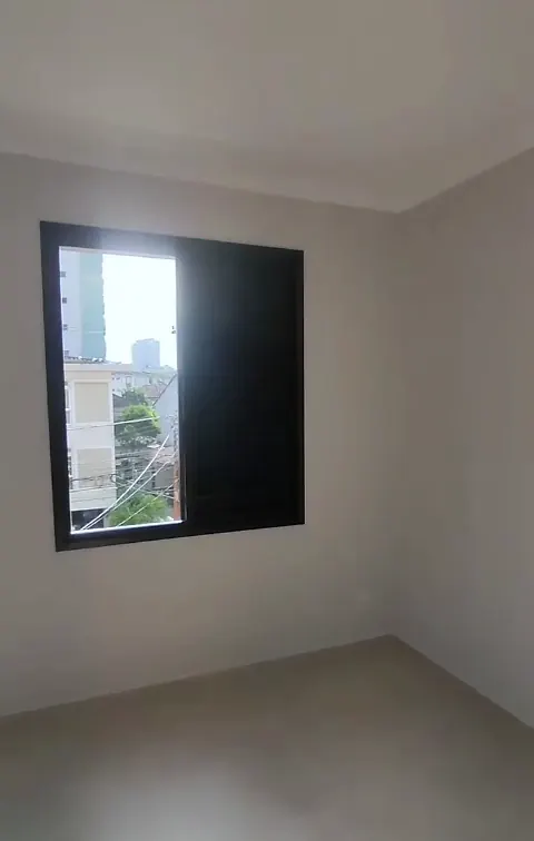Quarto vazio com paredes claras, piso novo e janela com veneziana escura