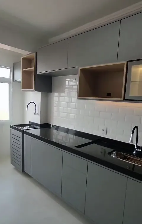 Cozinha finalizada com armários cinza, nicho em madeira, azulejo metrô branco e bancada preta
