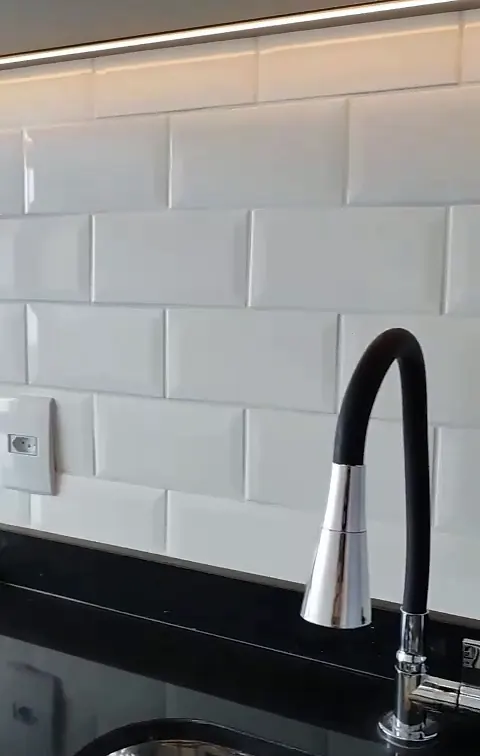 Detalhe do azulejo metrô branco e da torneira gourmet preta sobre a bancada